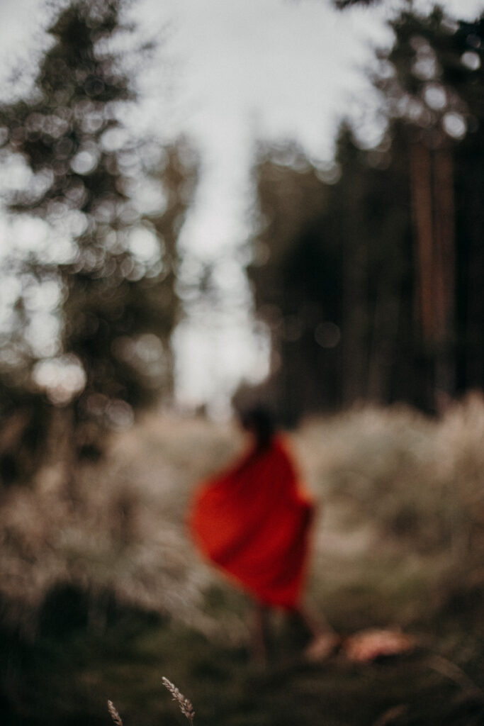 Frau mit rotem Umhang von der Seite gesehen im Wald